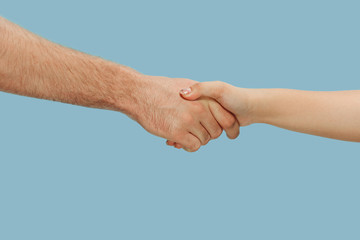 Closeup shot of human holding hands isolated on blue studio background. Concept of human relations, friendship, partnership, family. Copyspace.