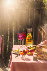 two colourful glasses of lemonade at table with rose tablecloth outside in garden summer picnic sun rays bright