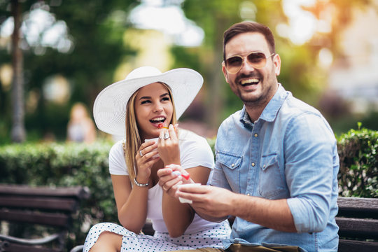 Couple joking and having fun while eating an ice cream in the park.