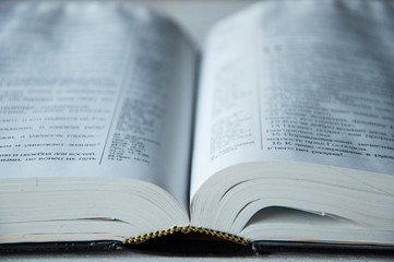 A large Bible book lies open on a wooden table. Close-up