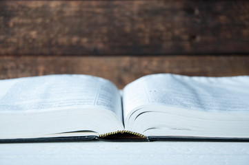 A large book lies open on a wooden table.