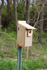 A close view of the old wood birdhouse on a pole.