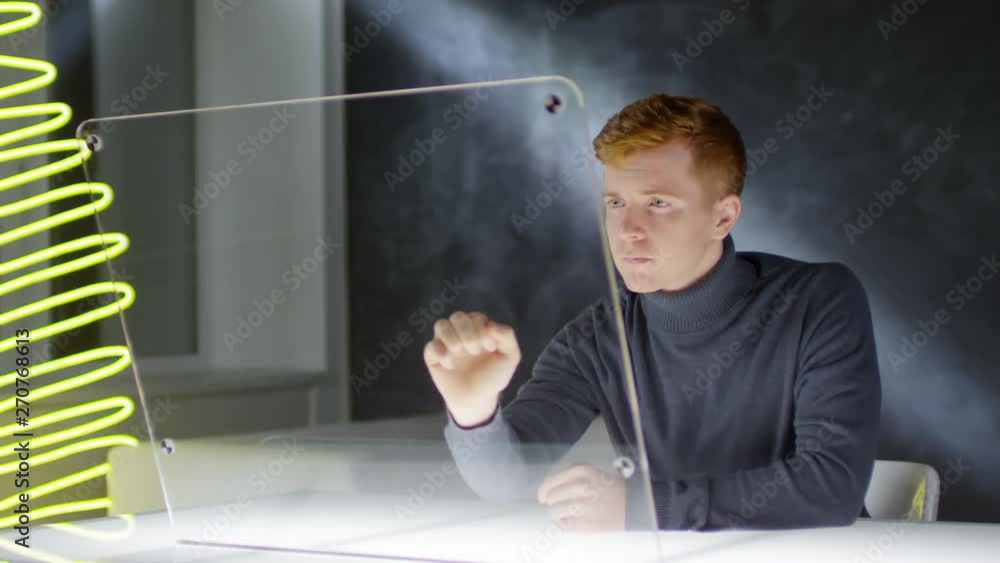 Aufkleber lockdown of young ginger man sitting at invisible multi-touch monitor and swiping webpages. footage 