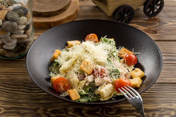 Healthy Grilled Chicken Caesar Salad with parmesan Cheese and Croutons on wooden table