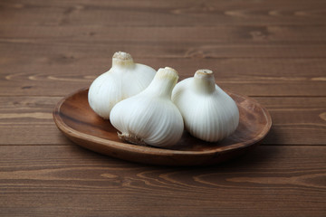 木のテーブルにのせた 生のニンニク ガーリック 木の皿