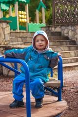 Smiling happy european little boy sitting on a colorful kids playground.