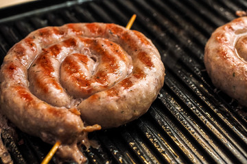 Fried spiral sausages on an electric barbecue BBQ grill. Homemade menu.
