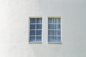 Two windows on the white wall of the house