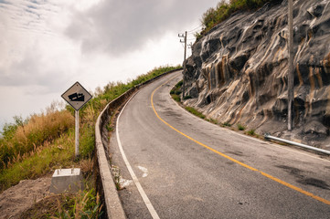 Winding mountain asphalt road with road sign to the sky in Khao Laem National park in Kanchanaburi Province of Thailand.