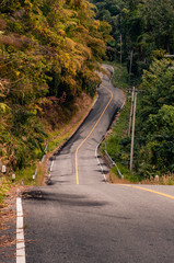 Winding mountain asphalt road through the autumn forest in Khao Laem National park in Kanchanaburi Province of Thailand.