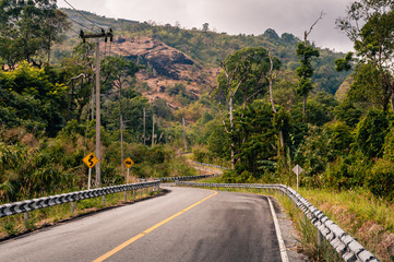 Winding mountain asphalt road through the autumn forest in Khao Laem National park in Kanchanaburi Province of Thailand.