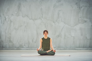Beutiful woman sitting on the mat in lotus posture.