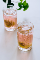 A glass of pink wine in a crystal glass on a marble background, green ivy and bright sun