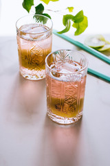 A glass of pink wine in a crystal glass on a marble background, green ivy and bright sun