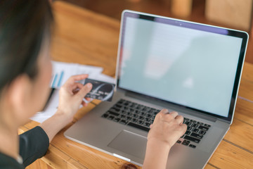 Hands holding a credit card and using laptop computer for online shopping .