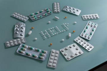 set of loose pills and complete tablets on green glass table