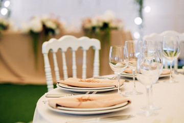 Wedding table service. Plates, glasses and flowers served on pink cloth