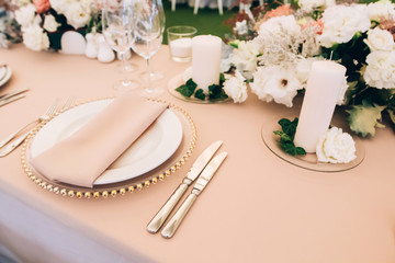 Wedding table service. Plates, glasses and flowers served on pink cloth