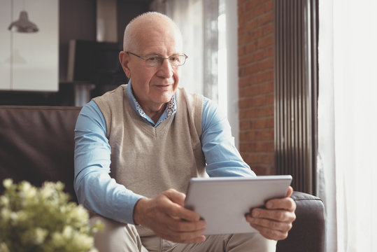Senior man using digital tablet in living room