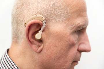 Hearing aid in the ear of aged old man