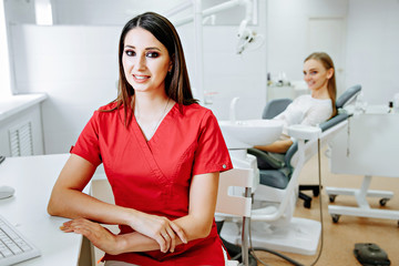 smart charming woman dentist sitting on computer desk, smile and looking at camera