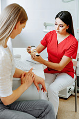 Concentrated dentist sitting at table and shows jaw samples tooth model to the patient