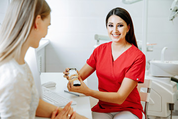 Obraz premium Concentrated dentist sitting at table and shows jaw samples tooth model to the patient
