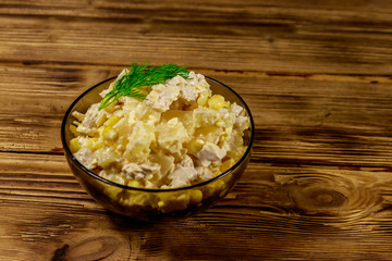 Festive salad with chicken breast, sweet corn, canned pineapple, cheese and mayonnaise on wooden...