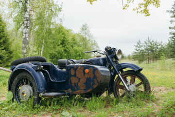 an old, rusty motorcycle with a sidecar stands alone in the woods