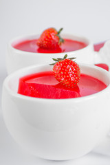 Vegetarian panacotta with strawberry and coconut milk in white cups on white background