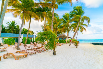 Beach chairs with umbrella at Maldives island, white sandy beach and sea .