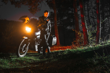 Headlights on, night forest. Adventure motorcycle, Motorcyclist in leather jacket, A motorbike...
