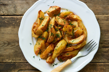 Baked potato slices with fresh dill on a white plate