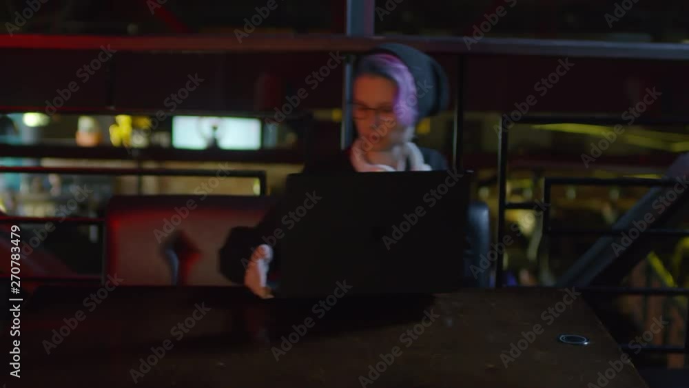 Poster zoom in of young female programmer sitting down at café table, putting laptop on table and starting 