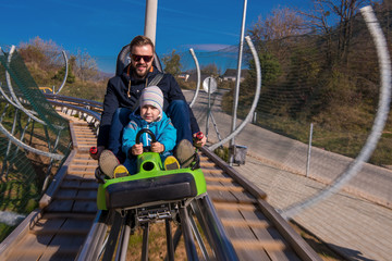 young father and son driving alpine coaster