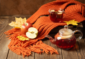 Drink autumn apple red berries in a glass teapot and an orange scarf on a wooden background. Hot...