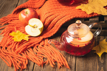 Drink autumn apple red berries in a glass teapot and an orange scarf on a wooden background. Hot...