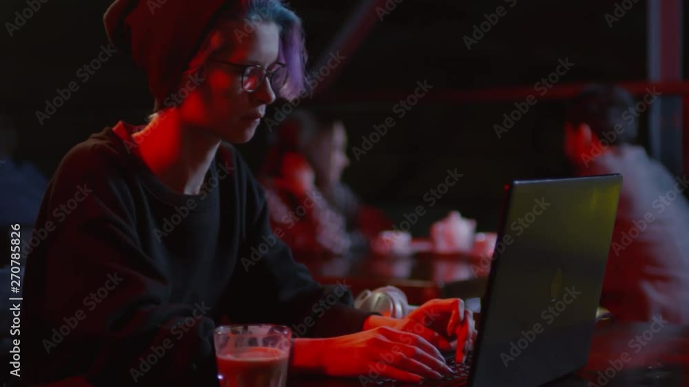 Aufkleber tilt down of female hacker sitting at bar table at laptop and creating new software