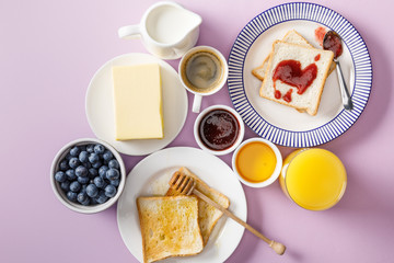 top view of served breakfast with cup of coffee and orange juice on violet background