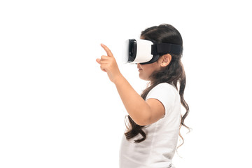 side view of latin kid pointing with finger while wearing virtual reality headset isolated on white