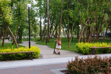 Cheerful little girl with shovel near the wooden fence in the park. Child works in garden. Childhood concept.