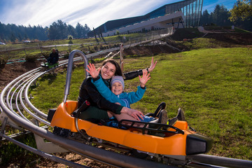 young mother and son driving alpine coaster