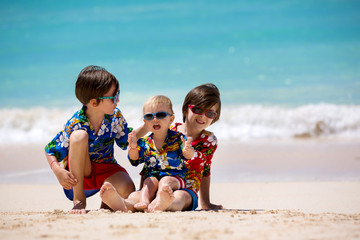 Happy beautiful fashion family, mom and children, dressed in hawaiian shirts, playing together on the beach