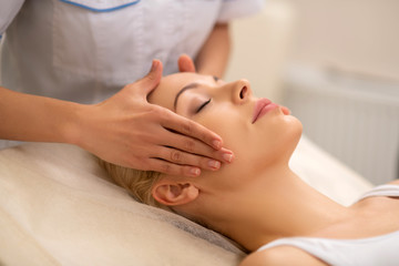 Obraz na płótnie Canvas Beautiful woman enjoying face massage in beauty center
