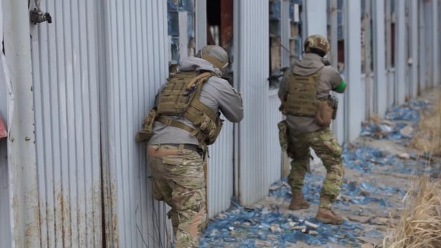  a team of military with weapons storming the building in which there are terrorists