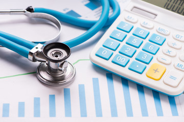 Medical practice financial analysis charts with stethoscope and calculator