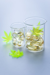 Pillen, Tabletten, Kapseln mit Cannabis Marihuana Hanf und CBD in Labor Becherglas gegen Schmerzen zur Therapie als Medizin 