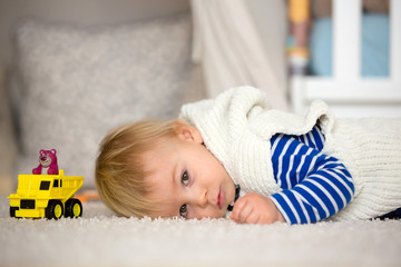 Sweet toddler boy, playing with car toys at home in kids room, child happiness concept