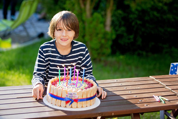Sweet preteen boy, celebrating his birhtday with colorful cake outdoors