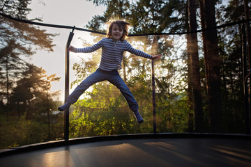 Sweet preteen boy jumping on trampoline making somersaults in the air. Happy child jumping on...